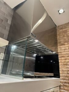 Area gourmet com Coifa industrial espelhada com duto de exaustão embutido