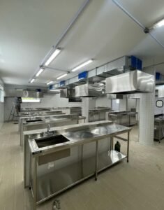 uma grande cozinha comercial com eletrodomésticos de aço inoxidável fabrica no rio de janeiro com sistema de ventilação e exaustão